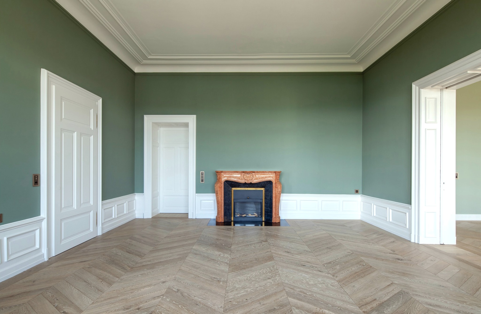 Altbau mit grünen Wänden, weißen Stuckdetails und Parkett