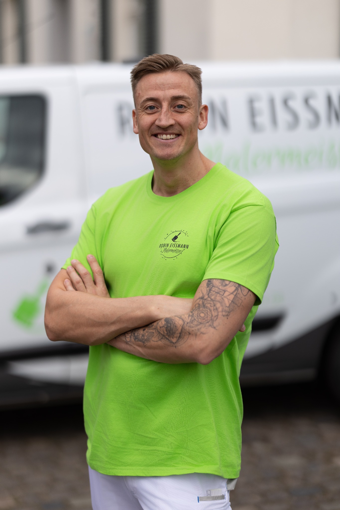 Robin Eissmann im grünen Firmenshirt vor seinem Fahrzeug